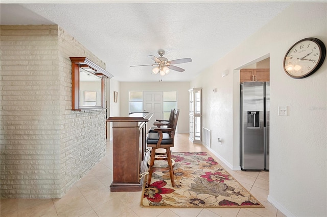 kitchen with stainless steel fridge with ice dispenser, light tile patterned flooring, a textured ceiling, and ceiling fan