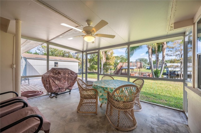 sunroom / solarium with ceiling fan and a water view