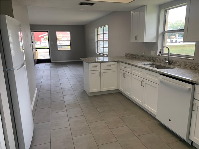 kitchen with kitchen peninsula, a wealth of natural light, white appliances, sink, and white cabinets