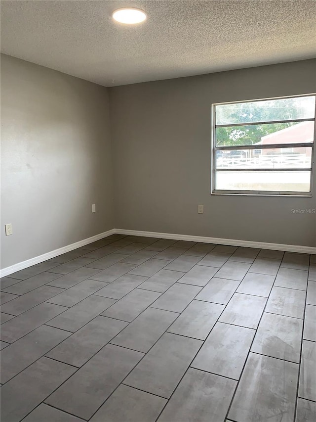 empty room with tile patterned floors and a textured ceiling