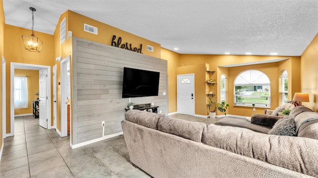 living room featuring vaulted ceiling, tile patterned floors, a chandelier, and a textured ceiling