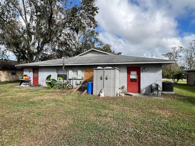 back of house with a yard and central AC