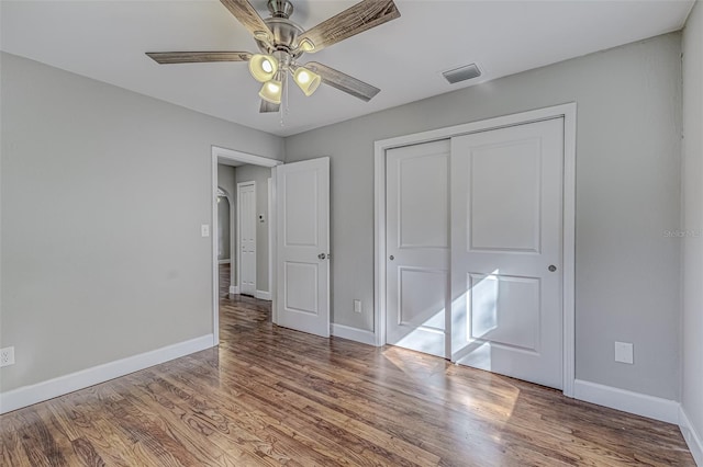 unfurnished bedroom featuring hardwood / wood-style floors, a closet, and ceiling fan