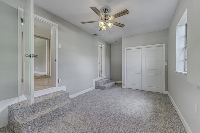 unfurnished bedroom with a closet, light colored carpet, and ceiling fan