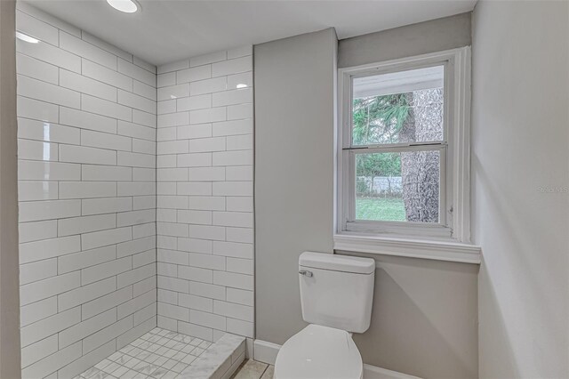 bathroom featuring a tile shower and toilet