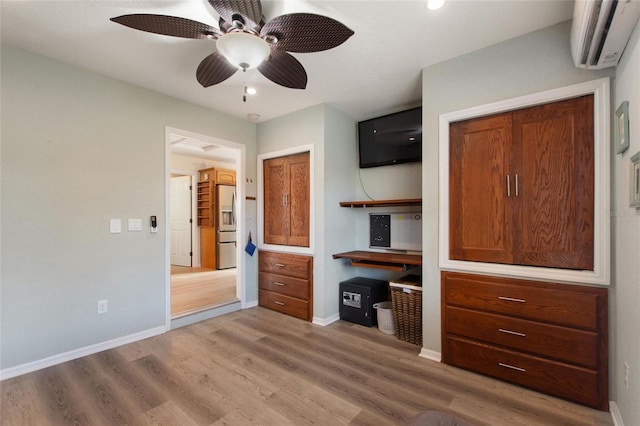 unfurnished bedroom featuring a wall mounted air conditioner, stainless steel fridge, ceiling fan, hardwood / wood-style floors, and a closet