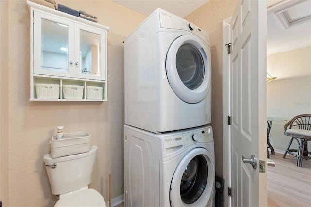 laundry room featuring light hardwood / wood-style floors and stacked washer / drying machine