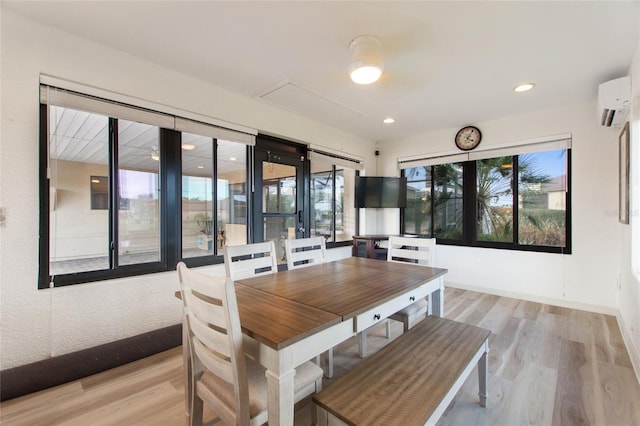 dining area with a wall unit AC and light wood-type flooring
