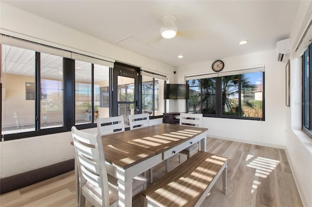 dining room featuring a wall mounted air conditioner, light hardwood / wood-style flooring, and plenty of natural light