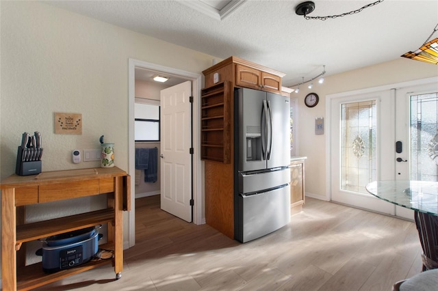 kitchen with stainless steel refrigerator with ice dispenser, a textured ceiling, light hardwood / wood-style floors, and french doors