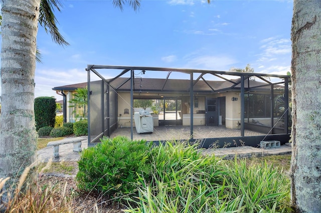 rear view of house with glass enclosure and a patio