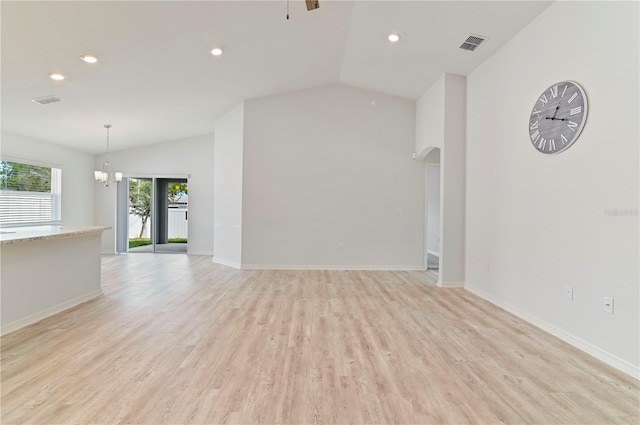 unfurnished living room featuring ceiling fan with notable chandelier, vaulted ceiling, and light hardwood / wood-style flooring