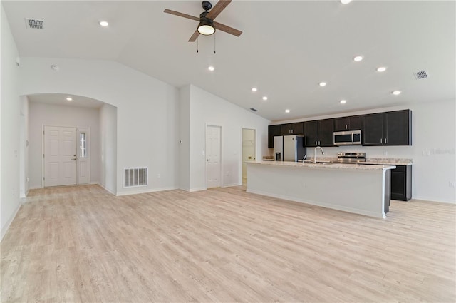 kitchen featuring sink, light hardwood / wood-style flooring, stainless steel appliances, light stone countertops, and a kitchen island with sink