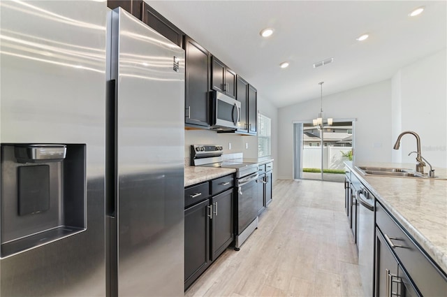 kitchen with lofted ceiling, sink, light wood-type flooring, pendant lighting, and stainless steel appliances