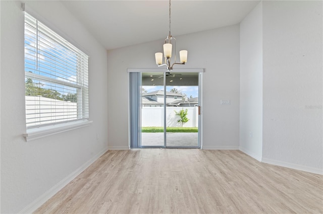 empty room featuring lofted ceiling, a chandelier, and light wood-type flooring