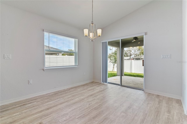 unfurnished room featuring lofted ceiling, a chandelier, and light wood-type flooring