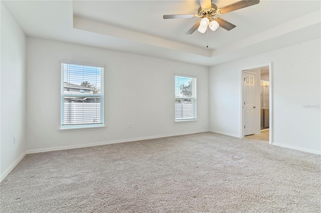 unfurnished room featuring light carpet, ceiling fan, and a tray ceiling