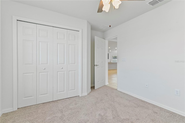 unfurnished bedroom featuring light colored carpet, a closet, and ceiling fan