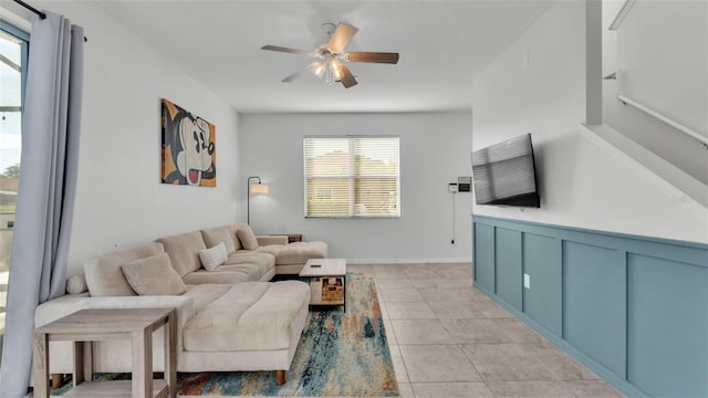 living room featuring light tile patterned flooring, a ceiling fan, and a decorative wall