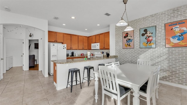 kitchen featuring visible vents, white appliances, arched walkways, a peninsula, and light stone countertops