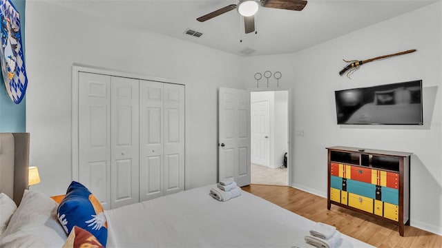 bedroom with a ceiling fan, wood finished floors, visible vents, and a closet