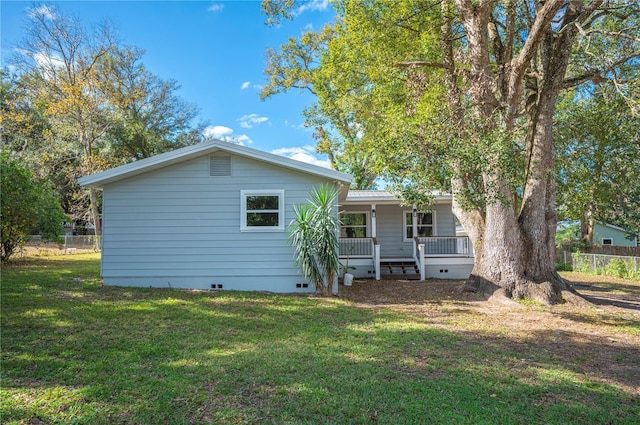 back of house featuring a lawn and covered porch