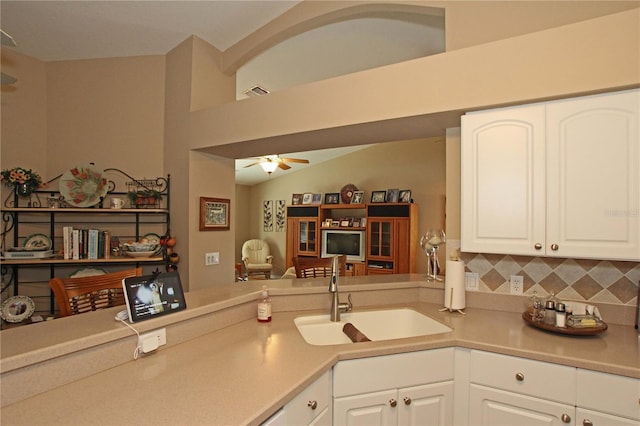 kitchen featuring kitchen peninsula, backsplash, ceiling fan, sink, and white cabinetry