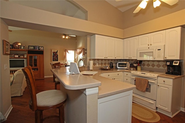 kitchen featuring kitchen peninsula, a breakfast bar, white appliances, dark wood-type flooring, and sink