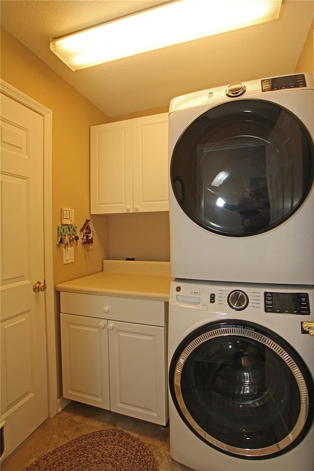 washroom featuring cabinets and stacked washing maching and dryer