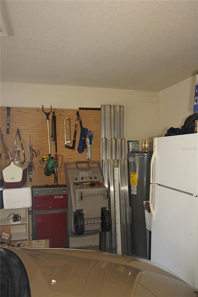 garage with a workshop area, electric water heater, and white fridge