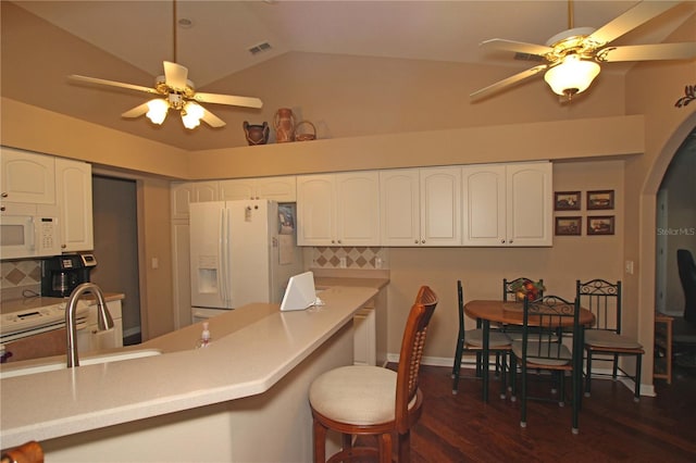 kitchen with backsplash, white appliances, vaulted ceiling, dark wood-type flooring, and sink