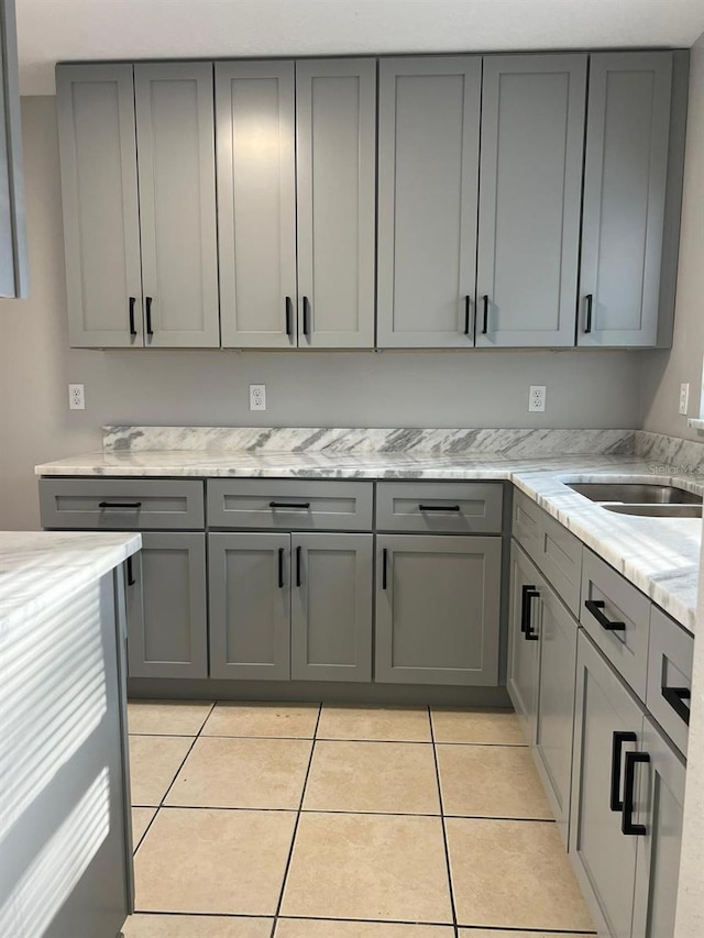 kitchen featuring light stone countertops, gray cabinetry, and light tile patterned flooring