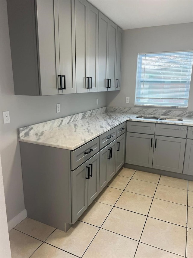 kitchen with light tile patterned floors, gray cabinetry, and sink