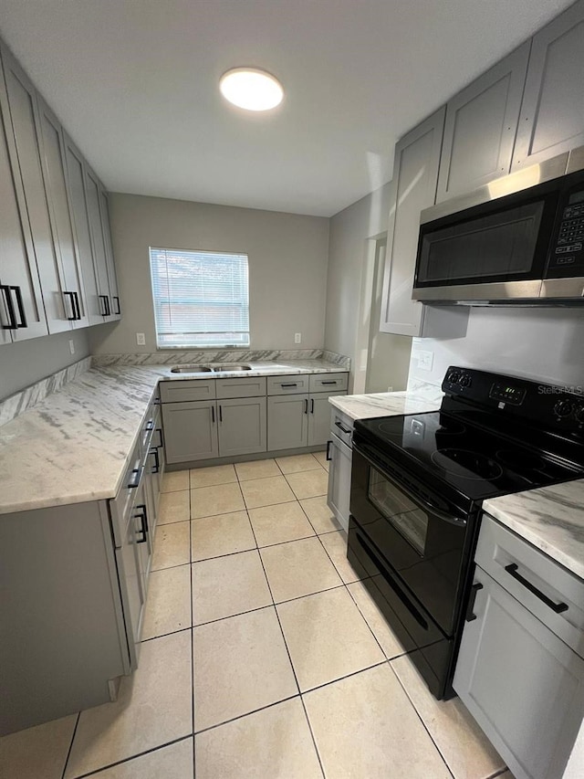 kitchen featuring light stone countertops, gray cabinetry, sink, light tile patterned floors, and electric range