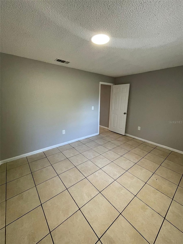 unfurnished room with light tile patterned flooring and a textured ceiling