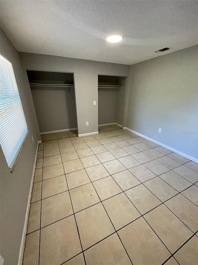 unfurnished bedroom featuring light tile patterned floors and a textured ceiling