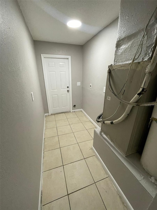 interior space with hookup for an electric dryer, light tile patterned floors, and a textured ceiling