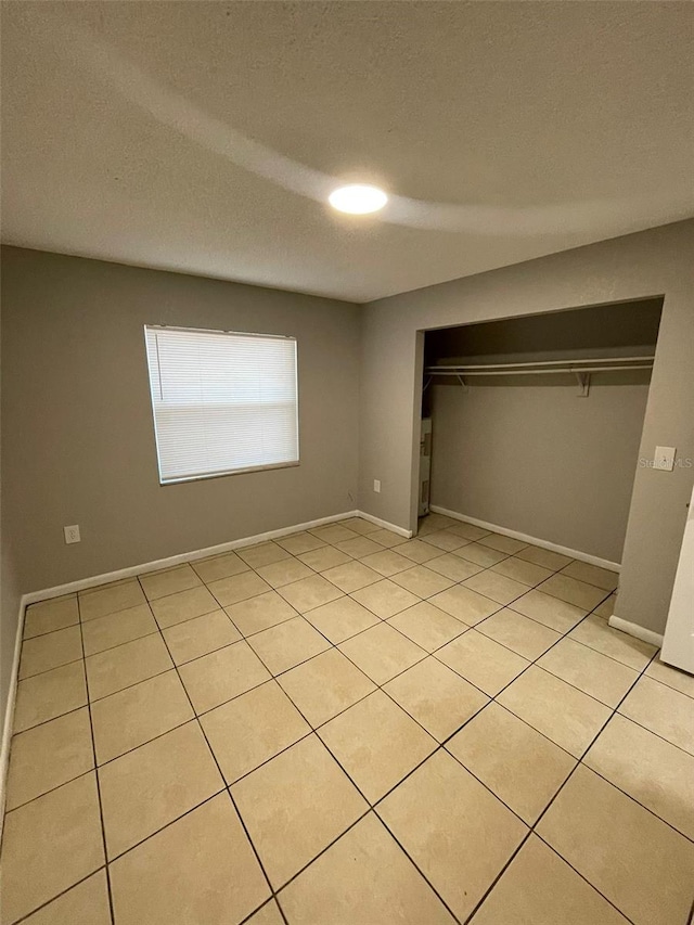 unfurnished bedroom featuring a closet, light tile patterned floors, and a textured ceiling