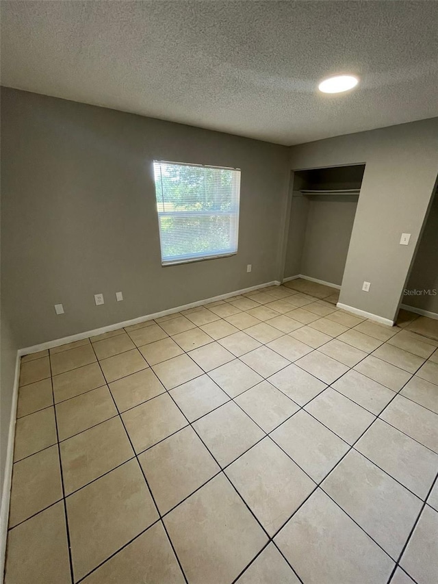 unfurnished bedroom with light tile patterned floors, a textured ceiling, and a closet