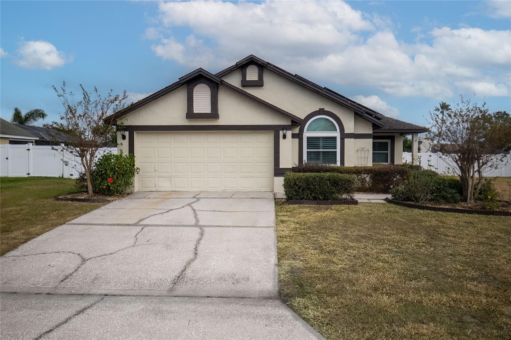 ranch-style home with a garage and a front lawn