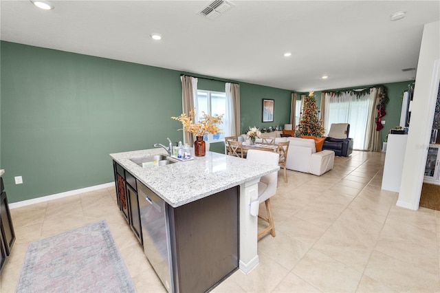 kitchen with dishwasher, dark brown cabinets, sink, and an island with sink