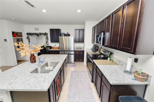 kitchen featuring sink, stainless steel appliances, a breakfast bar, light tile patterned flooring, and a center island with sink