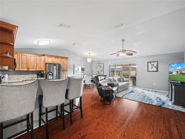 kitchen featuring ceiling fan, dark wood-type flooring, backsplash, stainless steel fridge, and vaulted ceiling