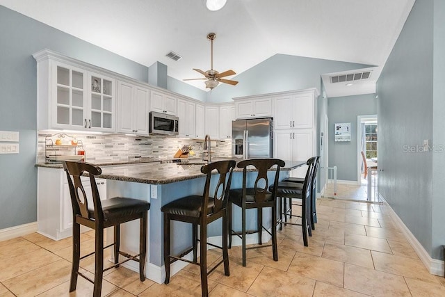 kitchen with white cabinets, sink, ceiling fan, appliances with stainless steel finishes, and a kitchen bar