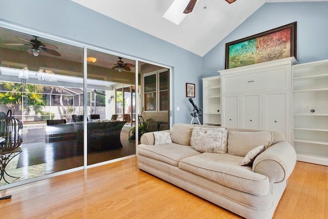 living room featuring wood-type flooring, a skylight, and high vaulted ceiling