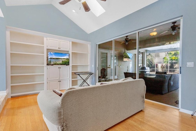 living room featuring light hardwood / wood-style floors, built in features, and vaulted ceiling with skylight