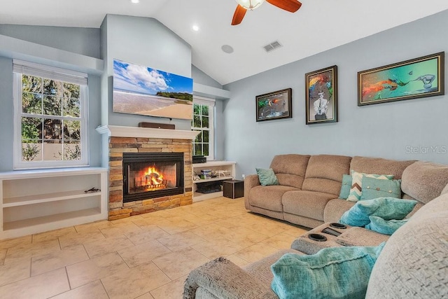 tiled living room with vaulted ceiling, ceiling fan, a healthy amount of sunlight, and a stone fireplace