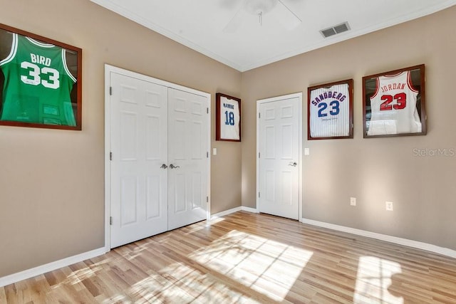 unfurnished bedroom featuring ceiling fan, crown molding, and hardwood / wood-style flooring