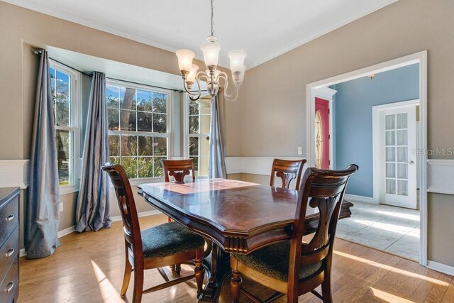 dining area featuring ornamental molding, light hardwood / wood-style floors, and an inviting chandelier