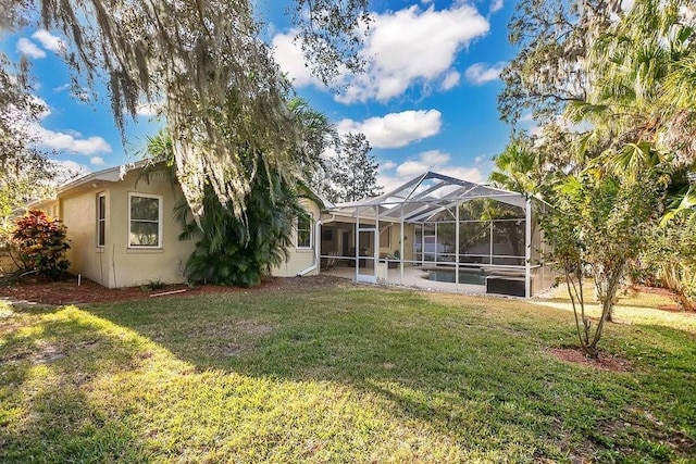 rear view of property featuring a lawn and glass enclosure